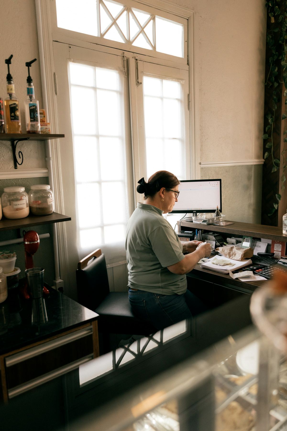A business owner works at the computer behind her shop counter